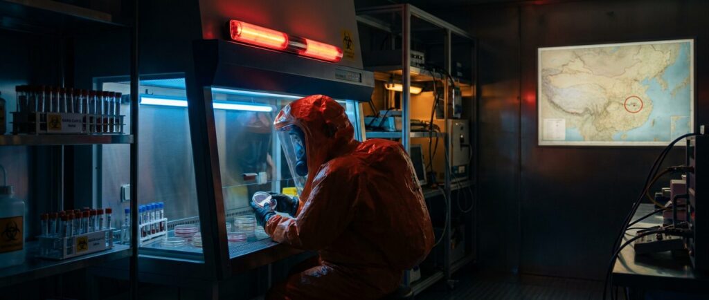 A scientist in hazmat gear in a Level 4 biosafety laboratory, representing gain-of-function research at the Wuhan Institute of Virology.